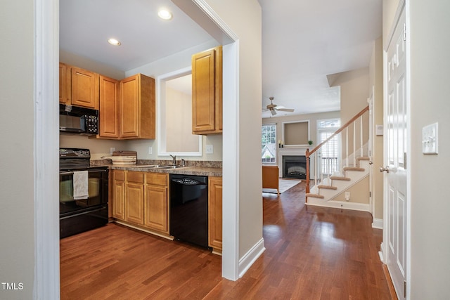 kitchen featuring black appliances, a fireplace, a ceiling fan, dark wood-style floors, and recessed lighting