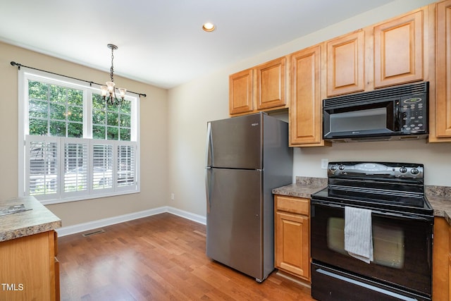 kitchen featuring black appliances, a chandelier, light wood-style flooring, baseboards, and hanging light fixtures