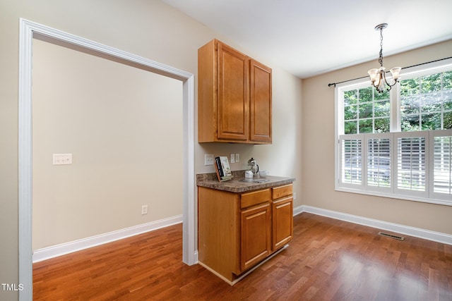 kitchen with dark wood finished floors, a chandelier, baseboards, and brown cabinets
