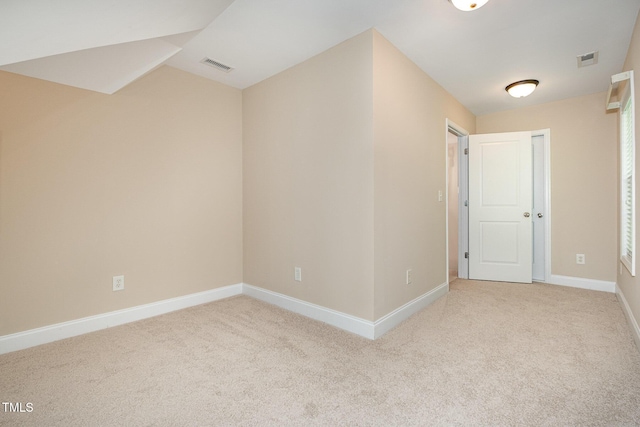 carpeted spare room featuring baseboards and vaulted ceiling