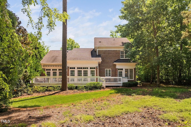 rear view of house with a yard, a deck, and brick siding