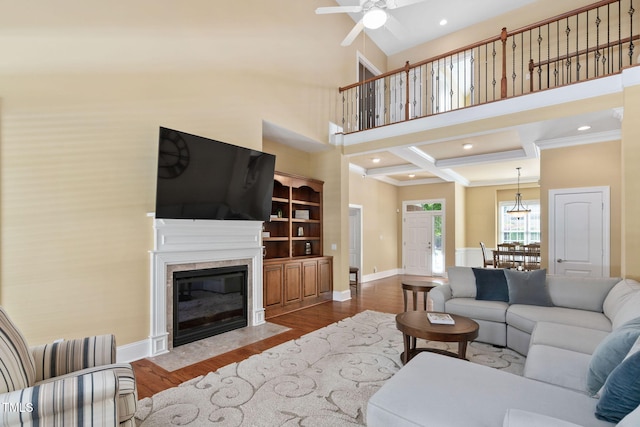 living area with wood finished floors, baseboards, a high ceiling, a ceiling fan, and a premium fireplace