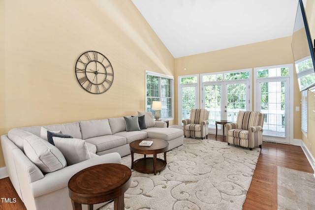 living room with baseboards, high vaulted ceiling, and wood finished floors