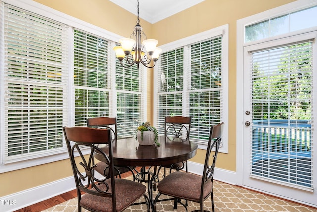 dining area featuring baseboards, ornamental molding, wood finished floors, and an inviting chandelier