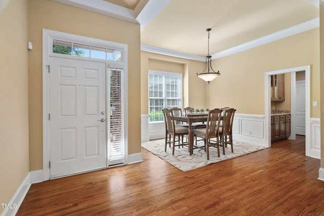 foyer entrance with crown molding, wainscoting, and wood finished floors