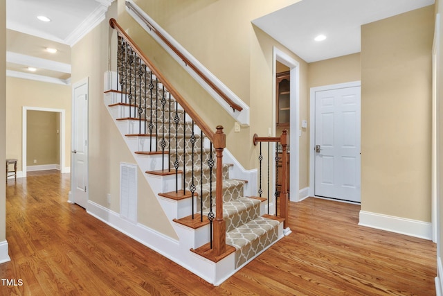 stairs with visible vents, wood finished floors, baseboards, ornamental molding, and recessed lighting