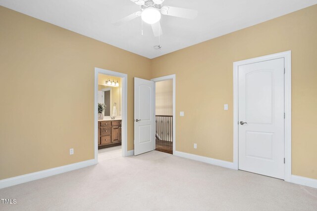 unfurnished bedroom with baseboards, ensuite bathroom, light carpet, and ceiling fan