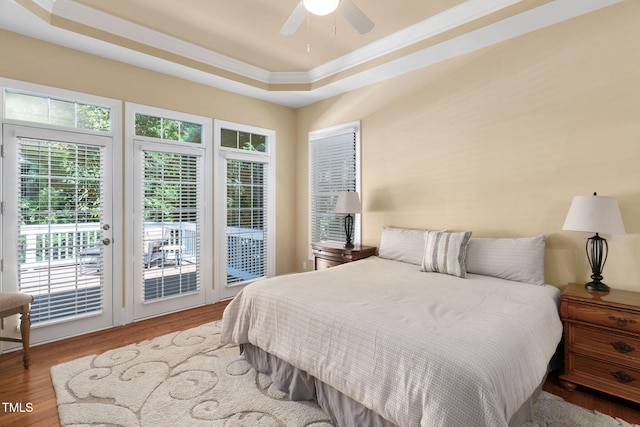 bedroom featuring crown molding, a raised ceiling, wood finished floors, and access to outside