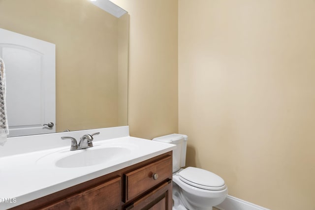 bathroom featuring toilet, baseboards, and vanity