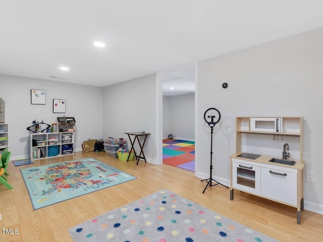 rec room featuring a sink, baseboards, light wood-style floors, and recessed lighting
