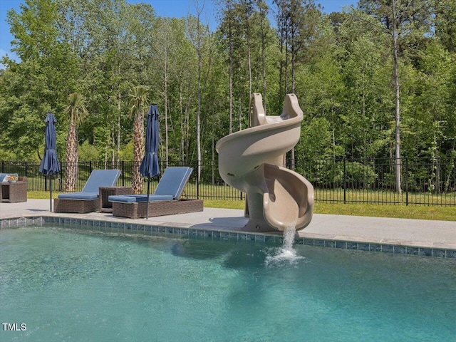 view of swimming pool with a fenced in pool, a patio area, a water slide, and fence