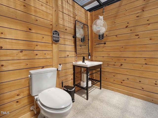 half bathroom featuring wood walls and toilet