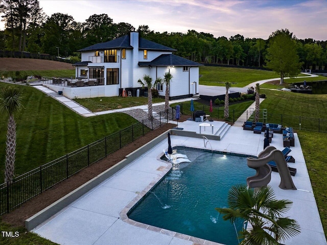 view of pool featuring a water slide, a fenced backyard, a fenced in pool, a patio area, and a lawn