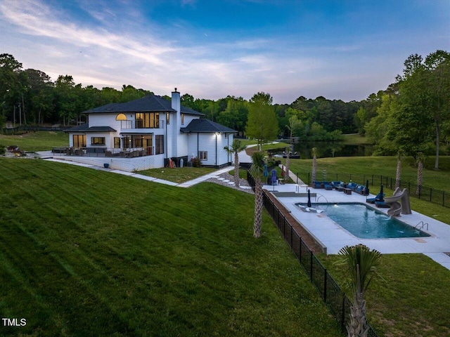 exterior space featuring a fenced backyard, a fenced in pool, a chimney, a patio area, and a yard