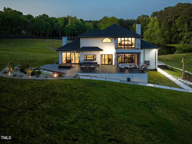 back of property featuring a view of trees, a chimney, a yard, and outdoor lounge area