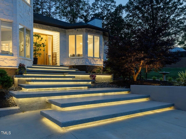 property entrance with a chimney and stone siding