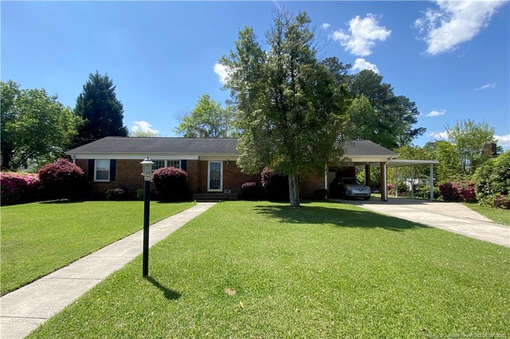 504 Highland Ave, Lumberton, NC 28358 - ranch-style house featuring driveway, an attached carport, a front lawn, and brick siding