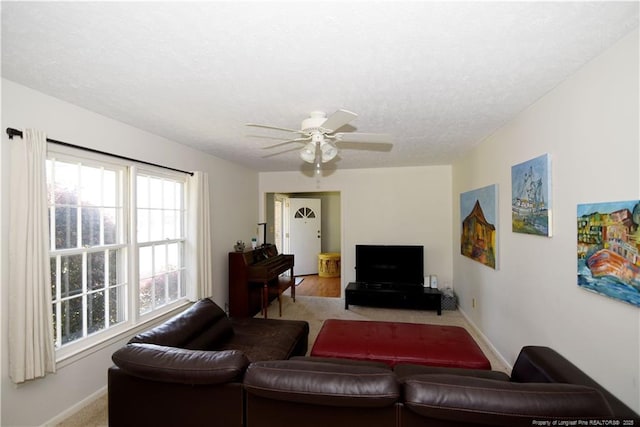 living area featuring baseboards, a textured ceiling, and ceiling fan