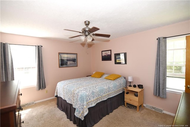 bedroom featuring light carpet, visible vents, multiple windows, and baseboards