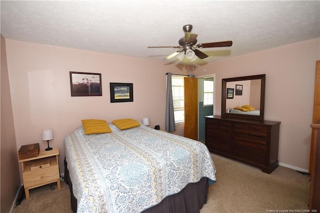bedroom featuring light carpet, ceiling fan, baseboards, and a textured ceiling
