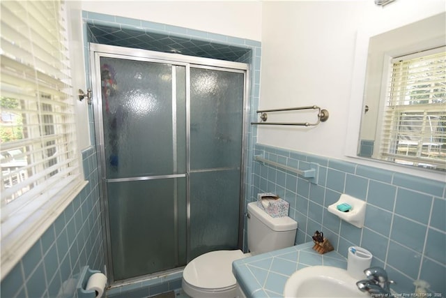 full bathroom with toilet, tile walls, a sink, and a stall shower