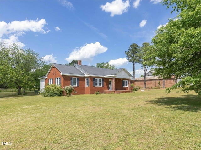 view of front of property with brick siding, a chimney, and a front lawn