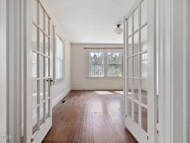 spare room featuring baseboards, visible vents, french doors, and hardwood / wood-style flooring
