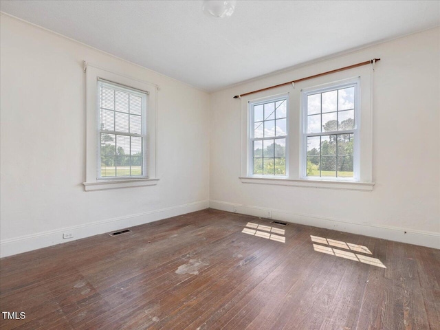 empty room featuring visible vents, wood-type flooring, and plenty of natural light