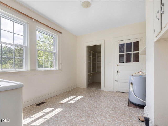 interior space with water heater, baseboards, and visible vents