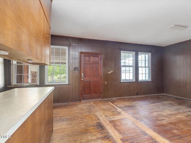 foyer with light wood-style floors, plenty of natural light, and wooden walls