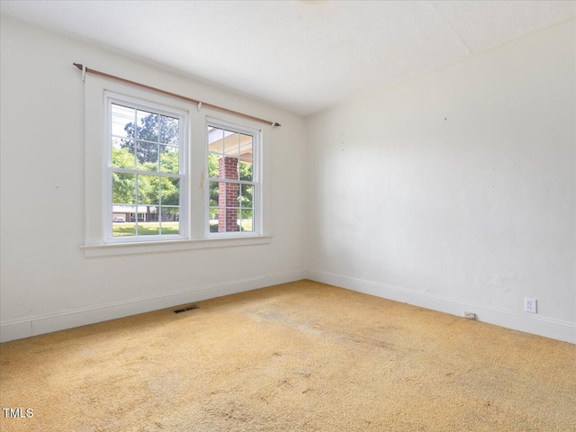 empty room with visible vents, carpet, and baseboards