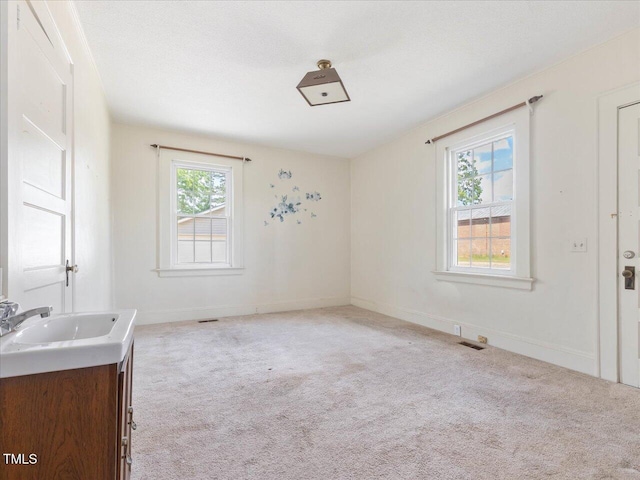 interior space with a sink, baseboards, carpet flooring, and visible vents