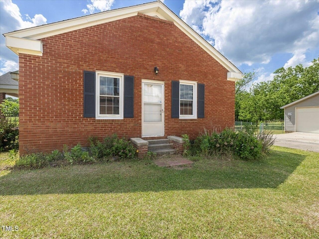 view of front of home featuring entry steps, fence, a front yard, and brick siding