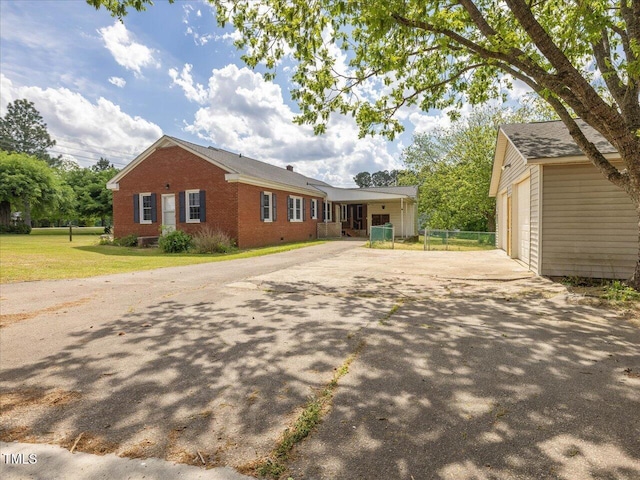 single story home with fence, brick siding, a front yard, an outbuilding, and concrete driveway