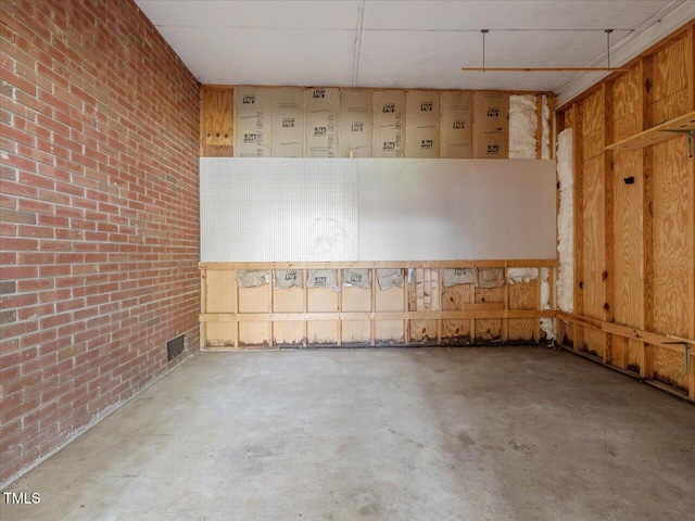 empty room featuring concrete floors, brick wall, and visible vents