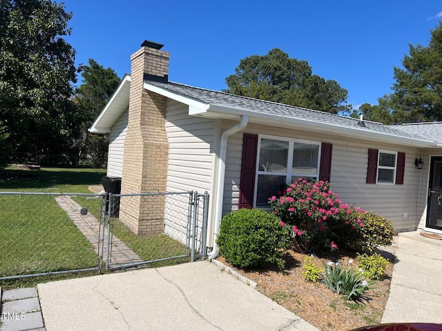 view of home's exterior with a lawn, a chimney, fence, a gate, and roof with shingles