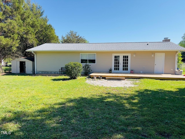 back of property with a lawn, a chimney, an outdoor structure, a storage unit, and french doors