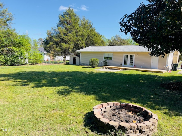 view of yard with french doors, an outdoor structure, an outdoor fire pit, and a storage unit