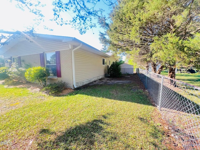 view of property exterior featuring brick siding, fence, and a lawn