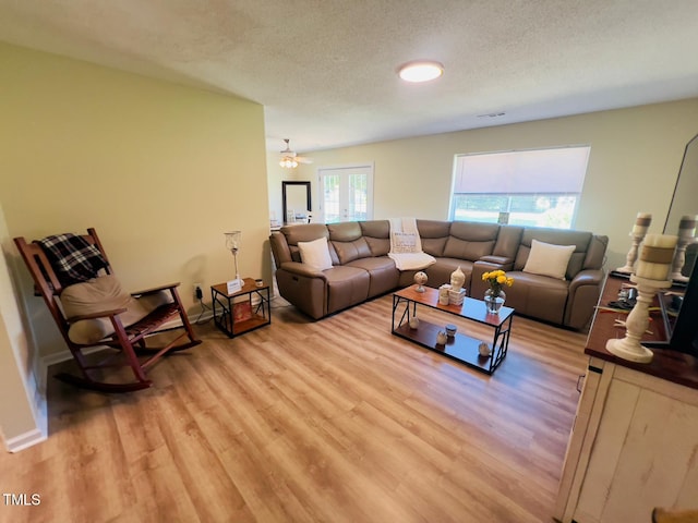 living area featuring light wood-style flooring, a textured ceiling, and visible vents