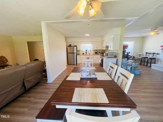 dining area with light wood finished floors, ceiling fan, and baseboards