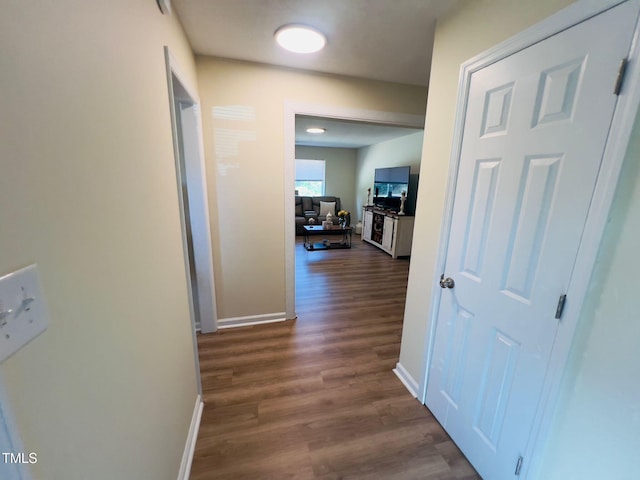 hall featuring dark wood-type flooring and baseboards