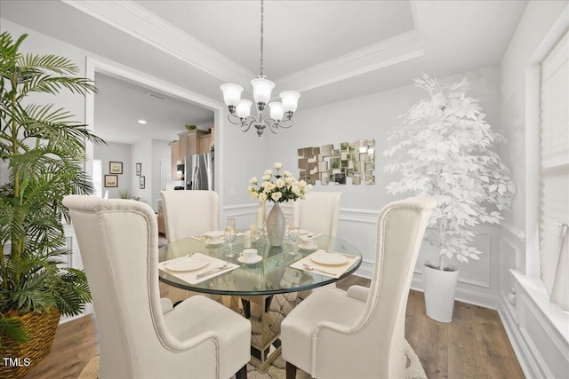 dining room with a decorative wall, a chandelier, wood finished floors, and crown molding