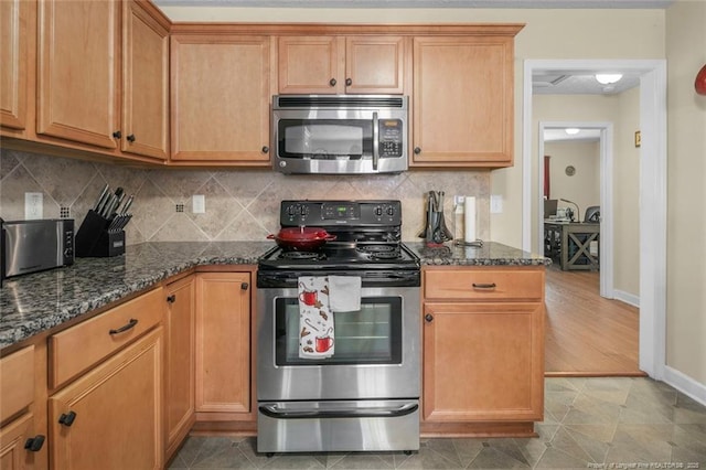 1114 Legend Creek Dr, Hope Mills, NC 28348 - kitchen with tasteful backsplash, baseboards, dark stone countertops, brown cabinets, and appliances with stainless steel finishes