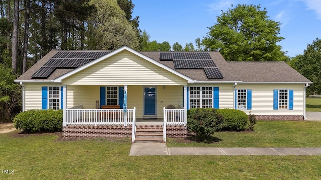 ranch-style home featuring a front lawn, roof mounted solar panels, covered porch, and roof with shingles