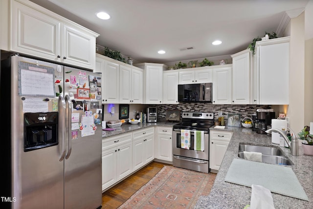 kitchen with white cabinets, backsplash, visible vents, a sink, and appliances with stainless steel finishes