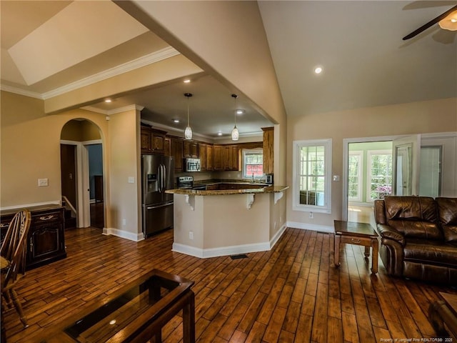 kitchen with a peninsula, open floor plan, ceiling fan, dark stone countertops, and stainless steel appliances