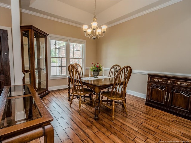 dining room featuring an inviting chandelier, baseboards, crown molding, and dark wood finished floors