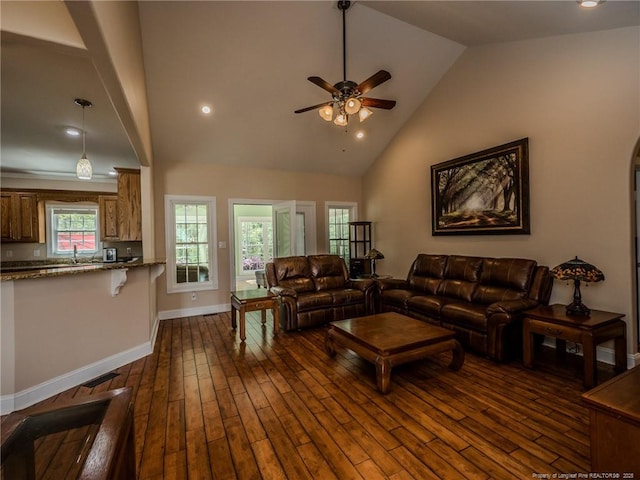 living area with a ceiling fan, high vaulted ceiling, dark wood-style floors, and baseboards