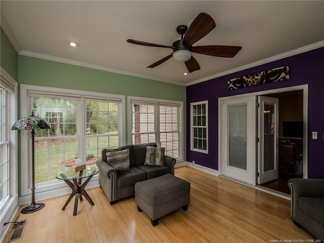 living room featuring crown molding, a ceiling fan, light wood finished floors, and visible vents